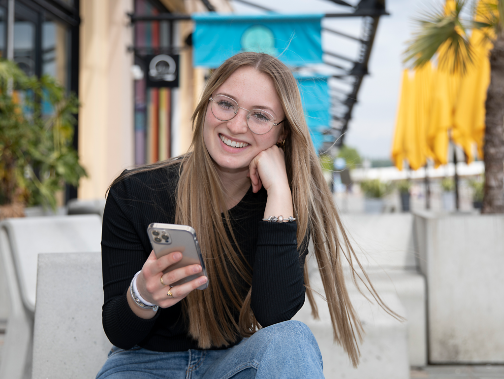student of the INSEEC Bachelor business school outside holding her smarthphone