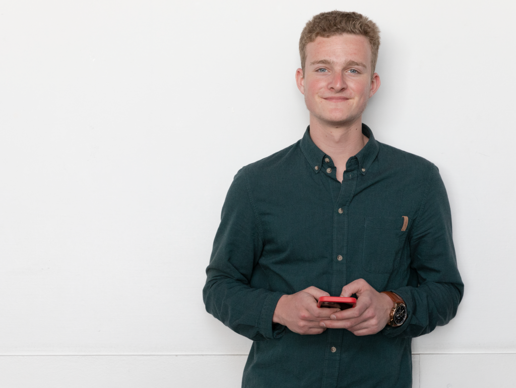 student of the INSEEC business school holding his mobile phone and smiling