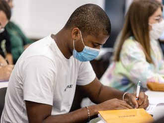 étudiant de l'INSEEC Bachelor avec un masque écrivant sur un papier