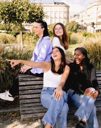 Group of students from the INSEEC business school sitting on a bench and laughing together