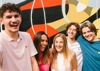 Group of students from the INSEEC business school laughing in front of a colourful tagged wall in Bordeaux