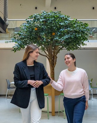 Étudiantes souriantes de l’école de commerce INSEEC devant l’oranger dans le hall du campus de Rennes