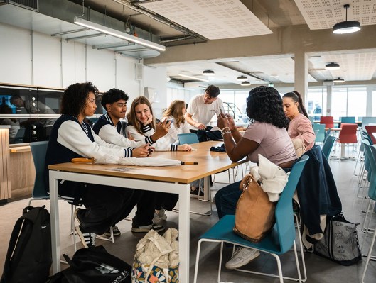 Groupe d’étudiants assis autour d’une table dans la cafétéria du campus de Bordeaux de l’école de commerce INSEEC