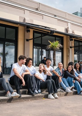 Groupe d’étudiants rigolant assis devant le campus de Bordeaux de l’école de commerce INSEEC