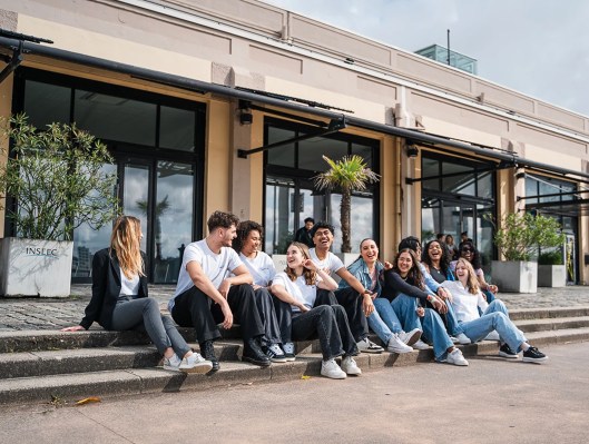 Groupe d’étudiants rigolant assis devant le campus de Bordeaux de l’école de commerce INSEEC
