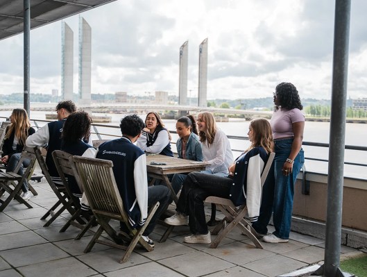 Groupe d’étudiants assis autour d’une table sur la terrasse en bord de Garonne du campus de Bordeaux de l’école de commerce INSEEC