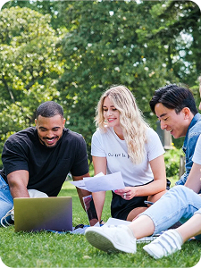 Étudiants travaillant devant un ordinateur sur l'herbe