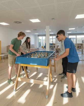 Étudiants jouant au baby-foot dans une salle spacieuse et lumineuse du campus de Barcelone