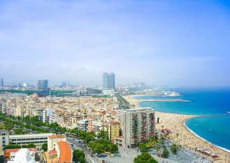 Vue aérienne de Barcelone montrant la plage de la Barceloneta, les immeubles côtiers et la mer Méditerranée sous un ciel clair