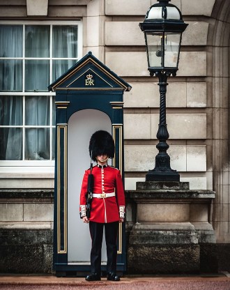 Garde royal britannique en uniforme rouge et bonnet à poils stationné dans une guérite devant un bâtiment officiel