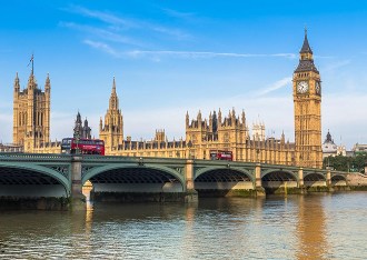 Vue du palais de Westminster et de Big Ben depuis la Tamise, avec des bus rouges traversant le pont de Westminster