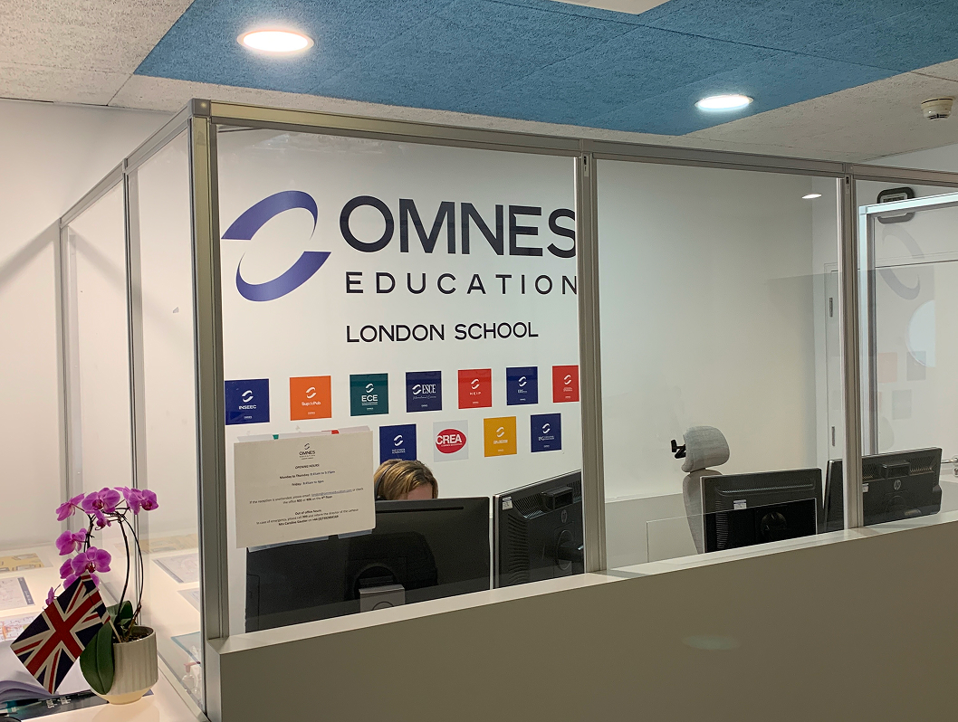 Accueil du campus OMNES Education à Londres avec comptoir, signalétique et drapeaux britanniques