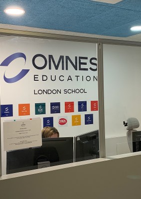 Accueil du campus OMNES Education à Londres avec comptoir, signalétique et drapeaux britanniques