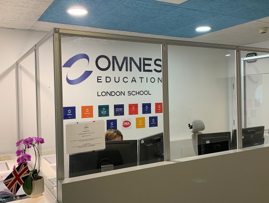 Accueil du campus OMNES Education à Londres avec comptoir, signalétique et drapeaux britanniques