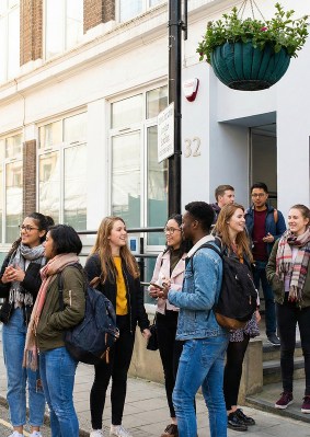 Étudiants sortant du campus OMNES Education de Londres, devant la façade vitrée d’un immeuble londonien