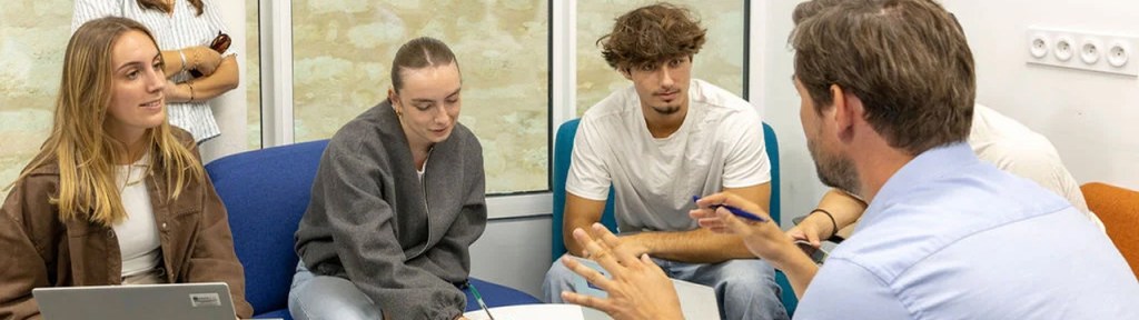 Groupe d’étudiants en discussion avec un coach autour d’une table lors d’un accompagnement de projets et d’idées de startup