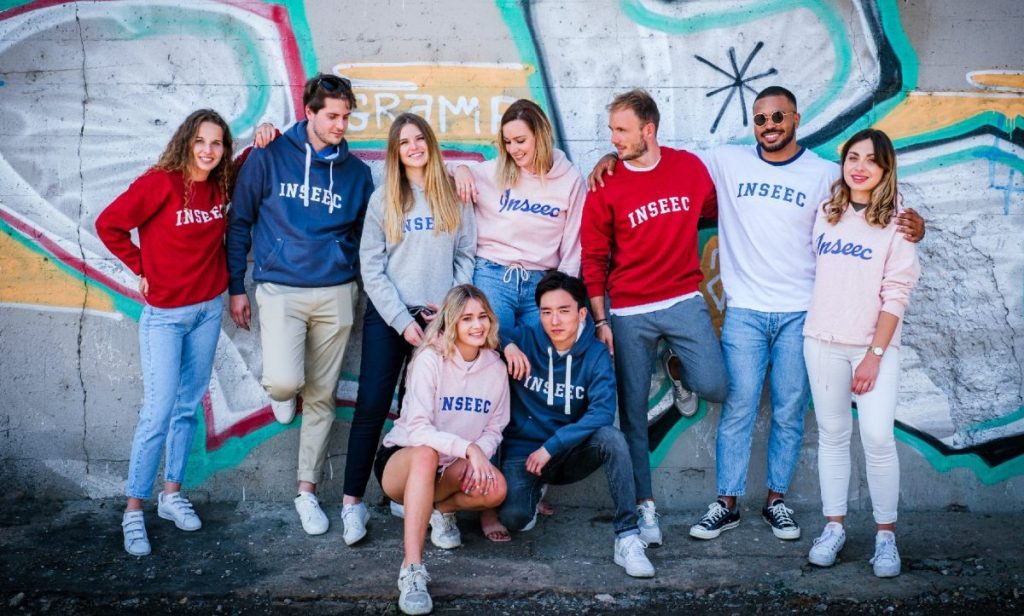 étudiants qui posent devant un mur avec des graffitis
