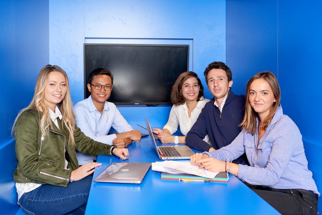 5 etudiants de l'INSEEC assis à un bureau, en train de travailler