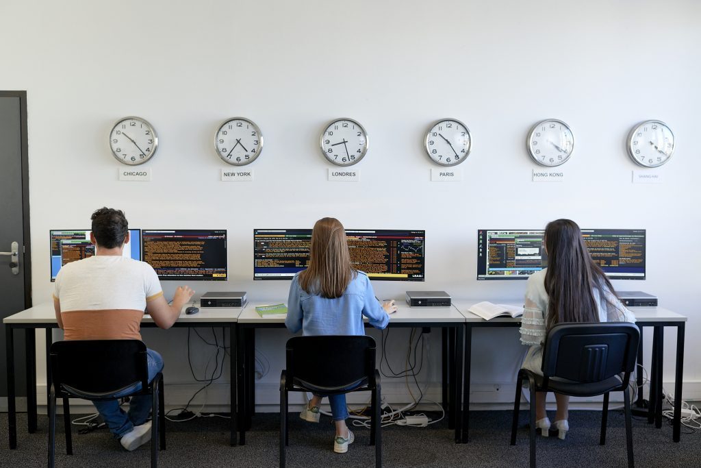 3 étudiants dans une salle informatique de finance de marché