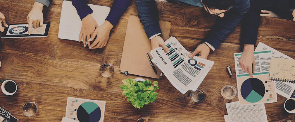 Table où travaillent des étudiants sur leur projet de finance, vue du haut, feuilles de projet et graphiques