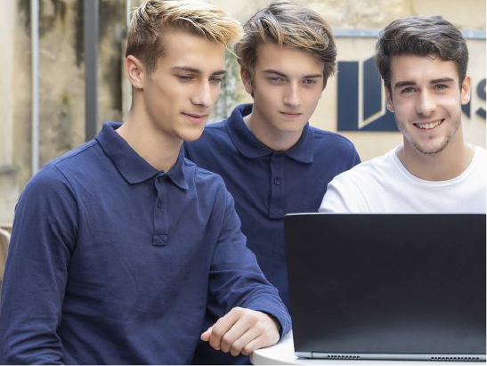 Students outside the building working on their course on a PC