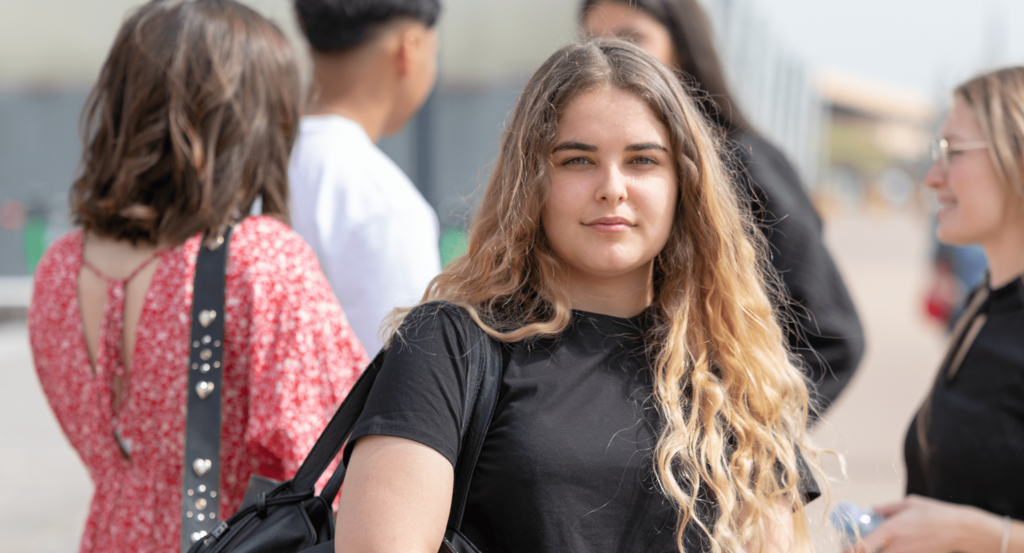 étudiante de l'école de commerce INSEEC se trouvant en extérieur à côté d'autres étudiants