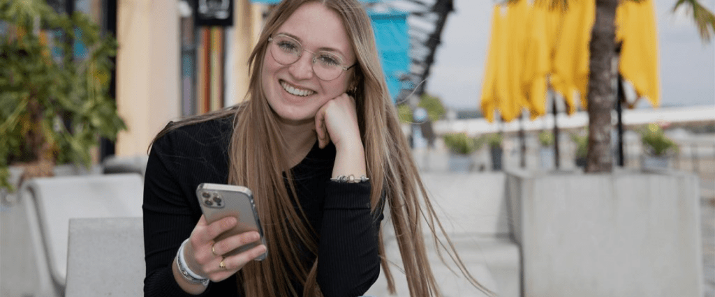 Etudiante qui sourit avec son telephone en main