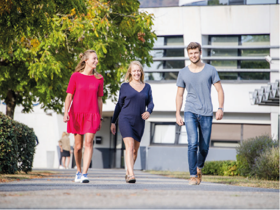 Etudiants qui sortent de leur journée de cours et qui marchent devant le campus. 