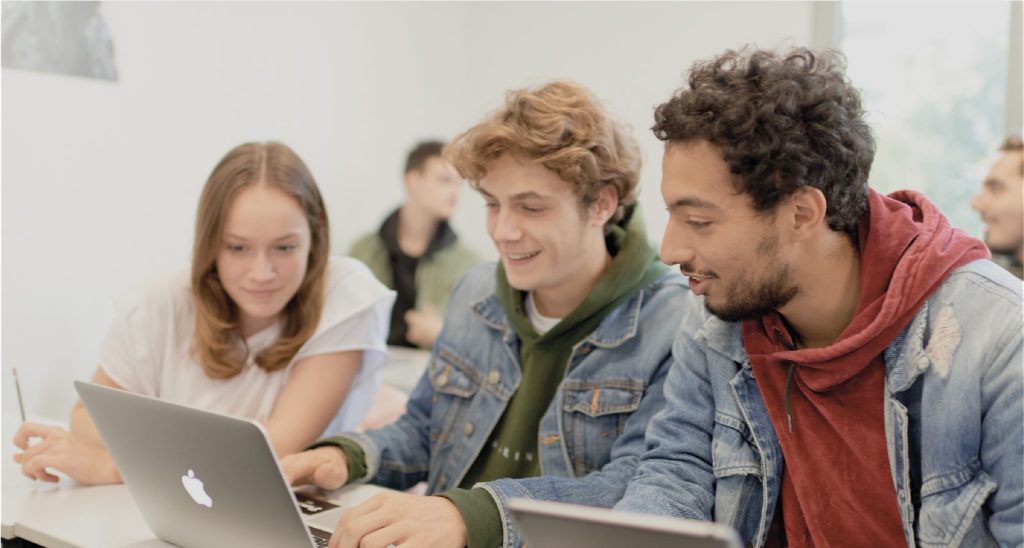 3 étudiants dans une salle de cours partageant leurs notes