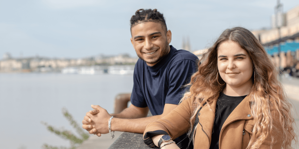 two students from the INSEEC business school standing on an outdoor embankment next to each other and smiling