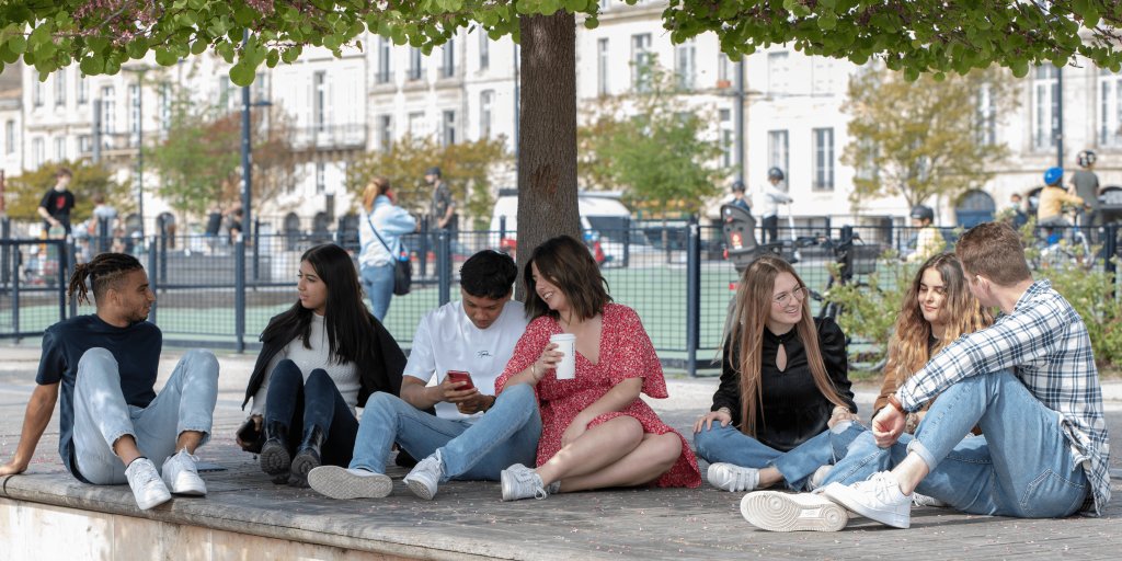 five students from the INSEEC business school sitting outside under a tree talking