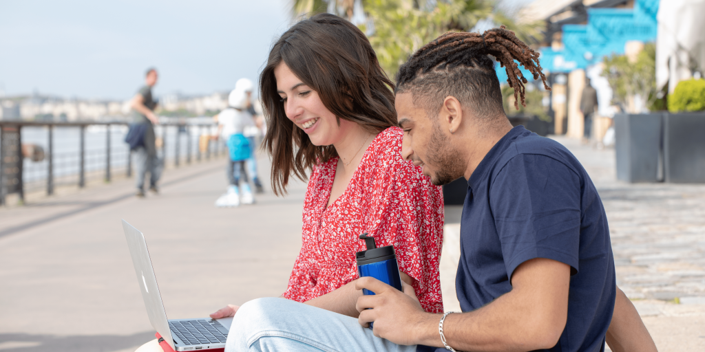 students from the INSEEC business school set up outside to work on their project around a computer