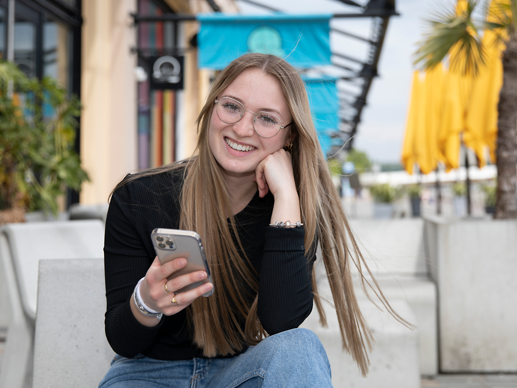 student of the INSEEC Bachelor business school outside holding her smarthphone